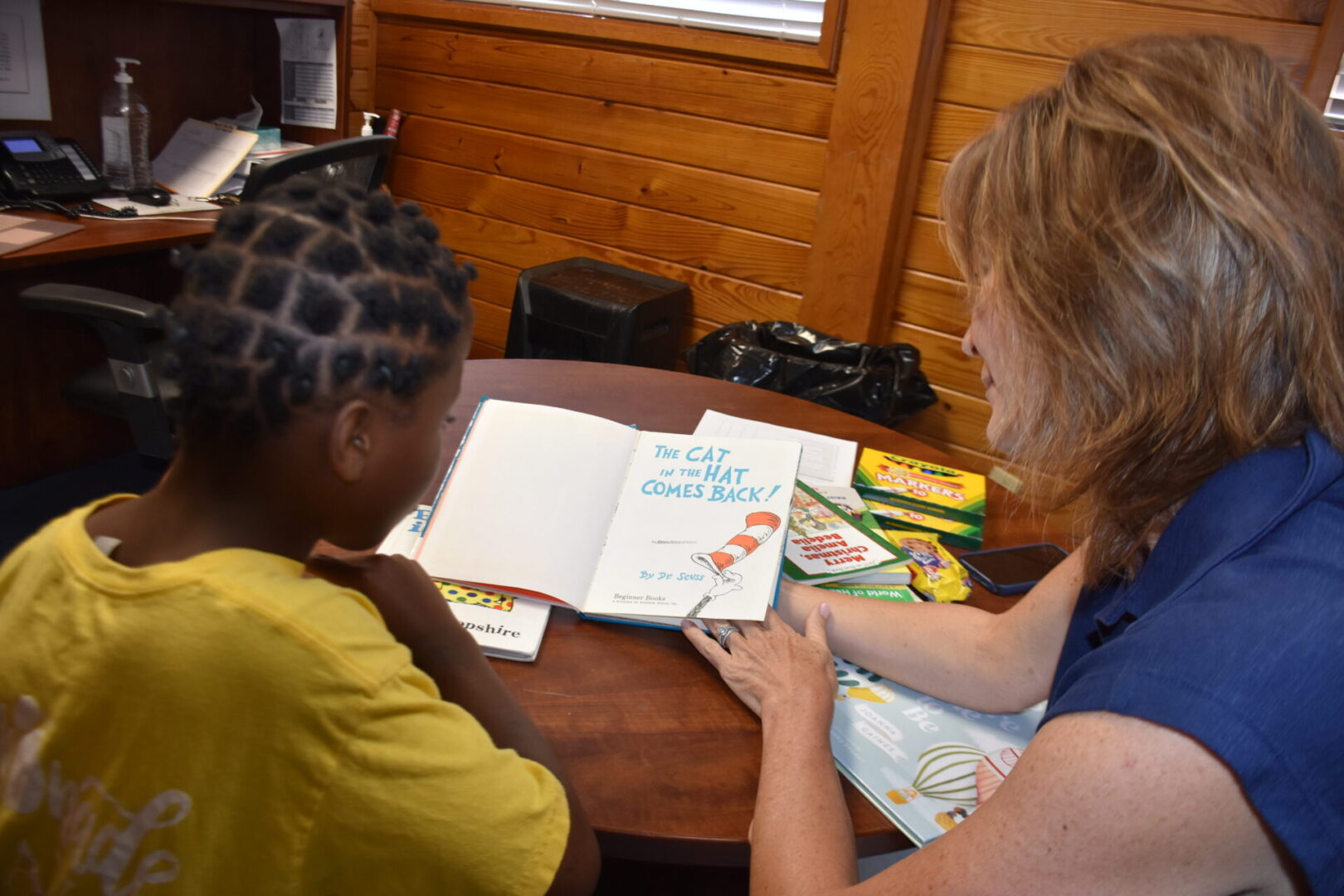 Woman reads "The Cat in the Hat" to girl.